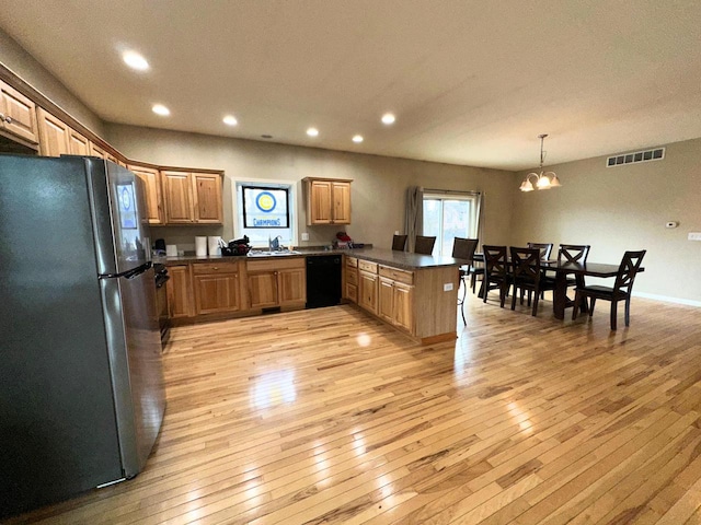 kitchen featuring dark countertops, visible vents, black dishwasher, light wood-style flooring, and freestanding refrigerator