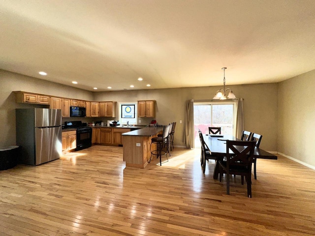 kitchen featuring black appliances, light wood-style flooring, dark countertops, a peninsula, and brown cabinetry