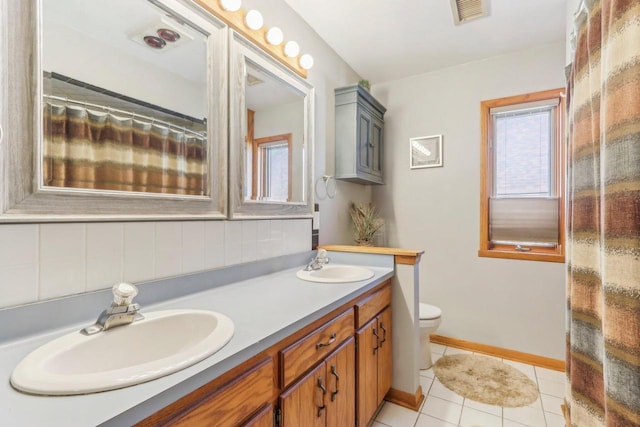 bathroom featuring double vanity, toilet, visible vents, and a sink