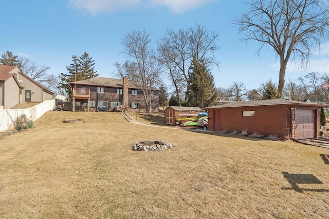 view of yard with a storage unit, fence, stairway, a fire pit, and an outdoor structure