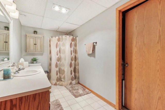 bathroom featuring a shower with curtain, tile patterned flooring, a paneled ceiling, baseboards, and vanity