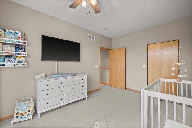 bedroom featuring visible vents, a crib, light carpet, a ceiling fan, and baseboards