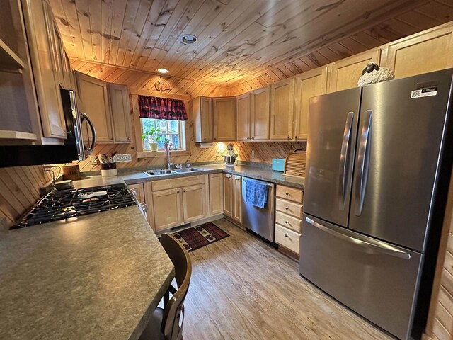 kitchen featuring stainless steel appliances, light wood-style flooring, wood walls, a sink, and wooden ceiling