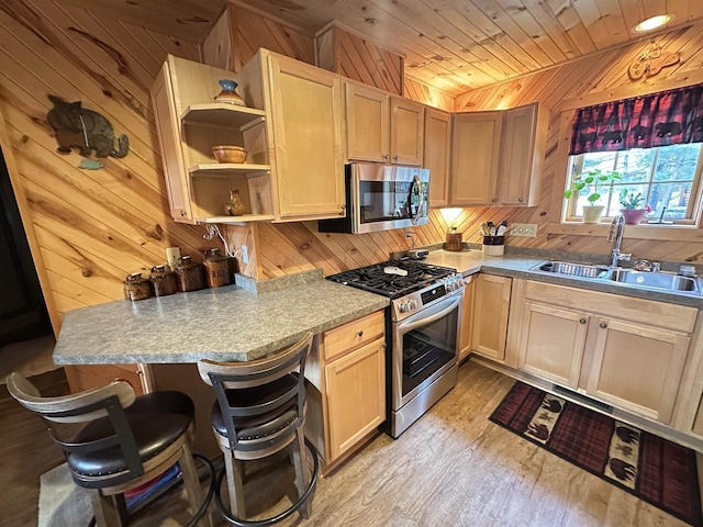 kitchen featuring stainless steel appliances, light wood-style flooring, a sink, wood walls, and wooden ceiling