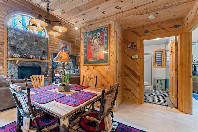 dining area featuring wood finished floors, rustic walls, a fireplace, and wood ceiling