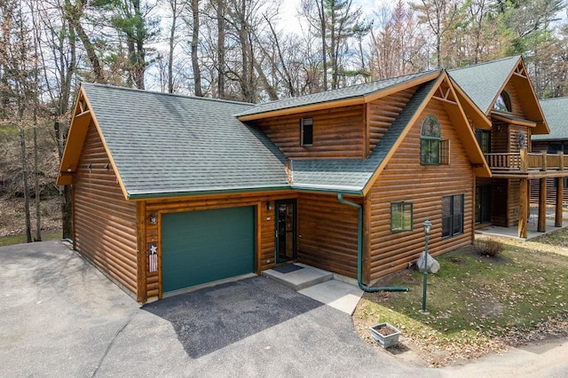 log home featuring an attached garage, a shingled roof, aphalt driveway, and log veneer siding