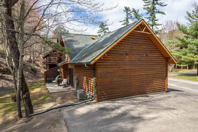 view of property exterior with roof with shingles and cooling unit