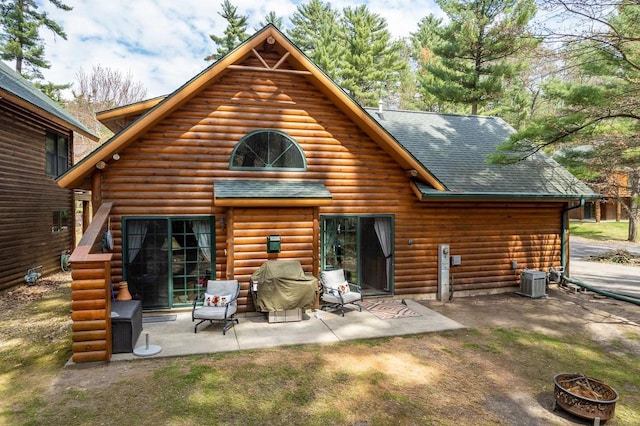 rear view of house with a fire pit, a shingled roof, central AC unit, and a patio area