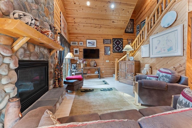 living area with wooden ceiling, wooden walls, stairway, and a stone fireplace