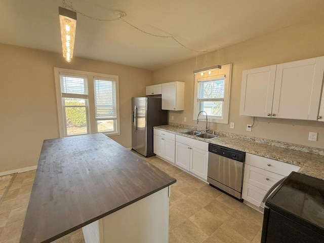 kitchen with stainless steel appliances, a sink, white cabinetry, and baseboards