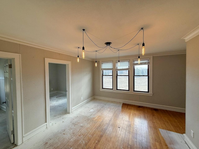 unfurnished dining area featuring light wood finished floors, baseboards, and crown molding