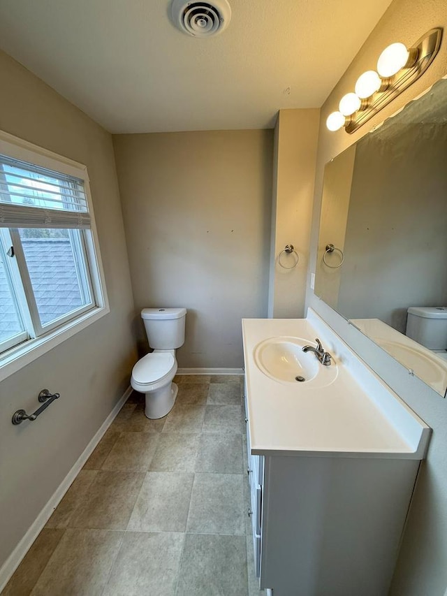 half bathroom featuring baseboards, visible vents, vanity, and toilet