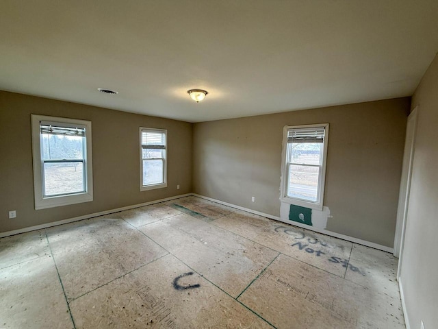 unfurnished room featuring a healthy amount of sunlight, visible vents, and baseboards