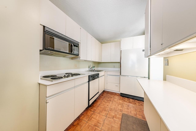 kitchen featuring black microwave, dishwashing machine, a textured ceiling, a sink, and freestanding refrigerator