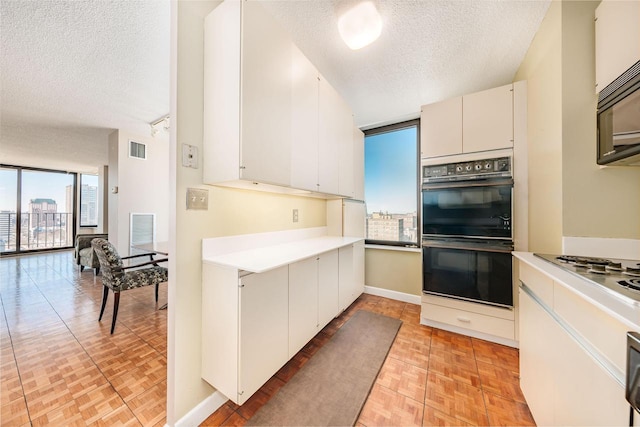 kitchen featuring a textured ceiling, black appliances, light countertops, and visible vents