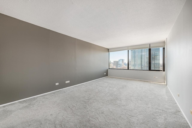 carpeted spare room featuring baseboards, a city view, and a textured ceiling