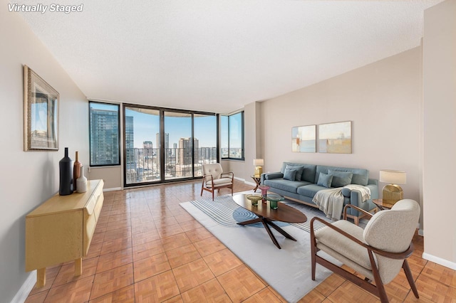 living room featuring a textured ceiling, floor to ceiling windows, baseboards, and a city view