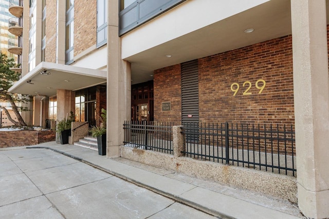 doorway to property with brick siding and fence