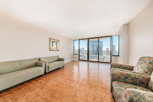 living area featuring baseboards, a view of city, floor to ceiling windows, and a textured ceiling