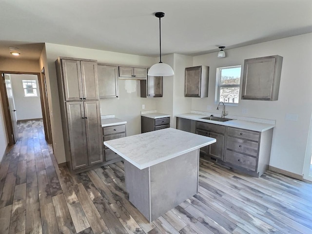 kitchen featuring pendant lighting, light countertops, a sink, and wood finished floors