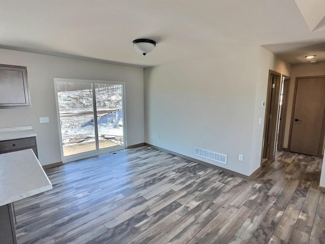 unfurnished dining area with wood finished floors, visible vents, and baseboards