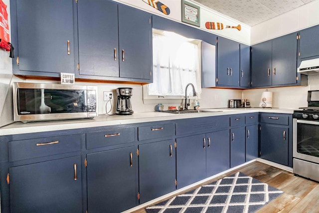 kitchen with light countertops, appliances with stainless steel finishes, dark wood-style flooring, and a sink