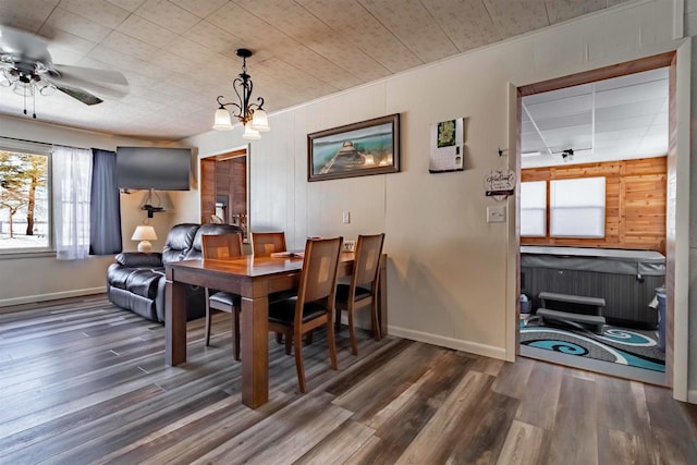 dining space with baseboards, wood finished floors, and ceiling fan with notable chandelier