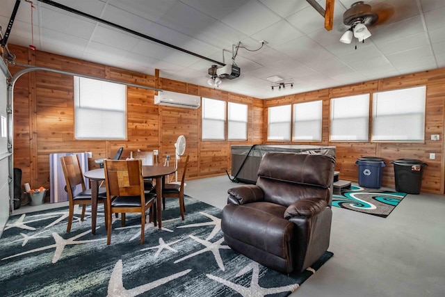 interior space with wood walls, finished concrete floors, track lighting, and a wall mounted AC