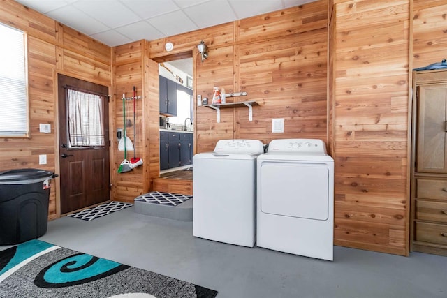 laundry area featuring wood walls and washer and dryer