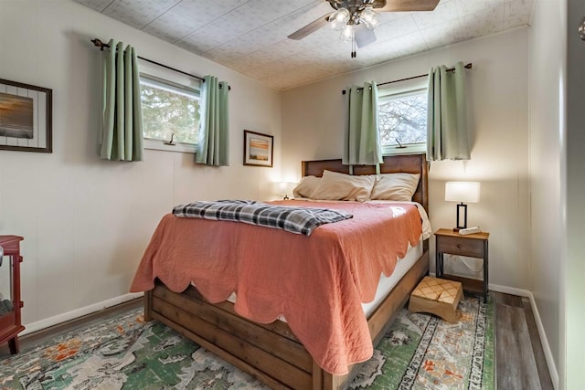 bedroom with ceiling fan, baseboards, and wood finished floors