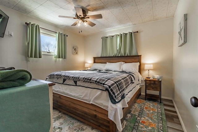 bedroom featuring ceiling fan, baseboards, and wood finished floors