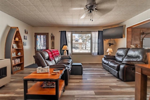 living area with a ceiling fan, baseboards, and wood finished floors