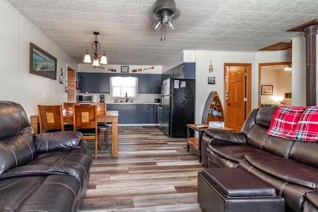 living area featuring light wood-style floors and ceiling fan with notable chandelier