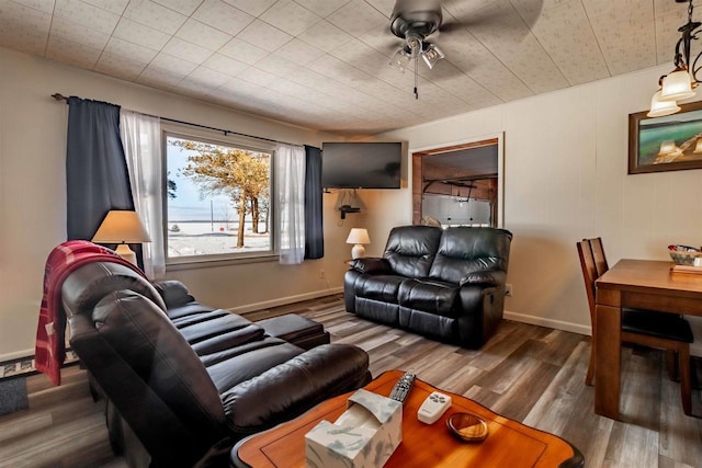 living room with wood finished floors, a ceiling fan, and baseboards