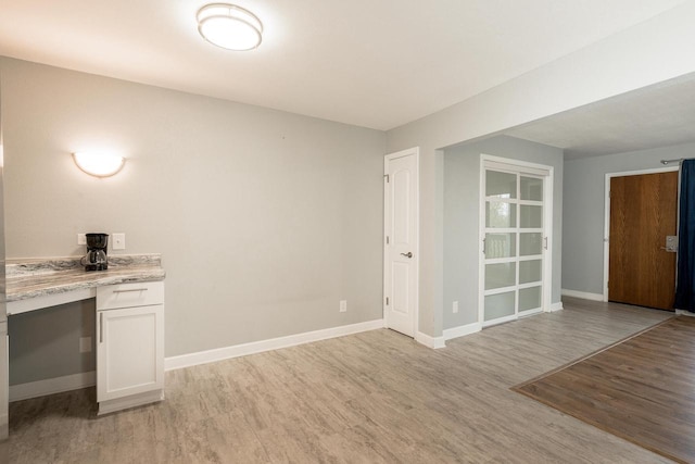 interior space featuring baseboards, light wood finished floors, and built in study area