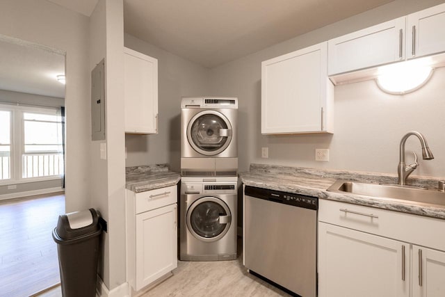 clothes washing area featuring light wood finished floors, stacked washing maching and dryer, a sink, and electric panel