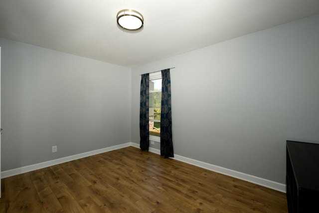 spare room with baseboards and wood finished floors