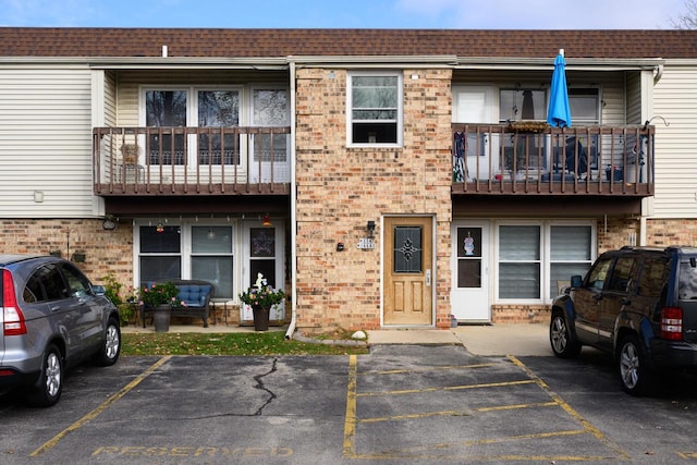 view of property featuring uncovered parking and brick siding