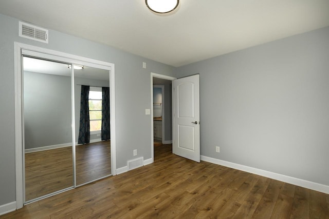 unfurnished bedroom with baseboards, a closet, visible vents, and wood finished floors