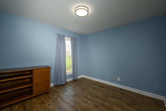 unfurnished bedroom with dark wood-style flooring and baseboards