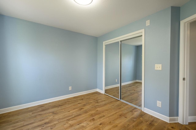 unfurnished bedroom with a closet, wood finished floors, and baseboards