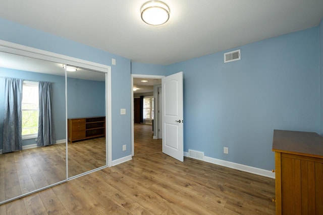 unfurnished bedroom with hardwood / wood-style floors, visible vents, and baseboards