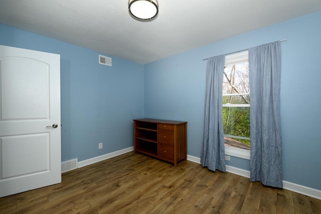 unfurnished bedroom with baseboards, visible vents, and wood finished floors