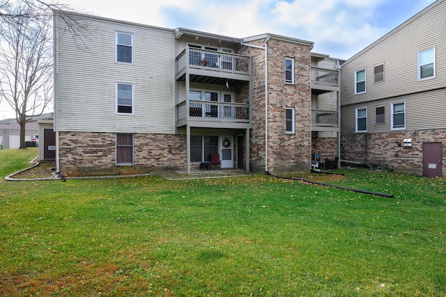 back of property featuring a lawn and brick siding