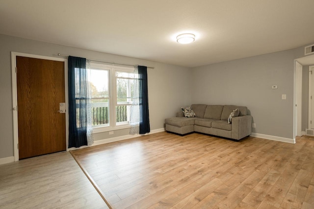 unfurnished living room featuring light wood finished floors, visible vents, and baseboards