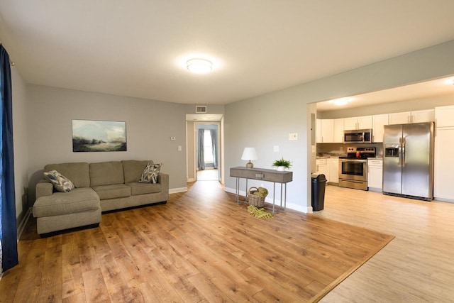 living room featuring light wood-style floors, visible vents, and baseboards