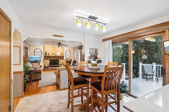 dining space with a fireplace, arched walkways, and a ceiling fan