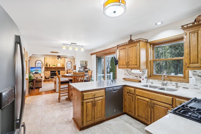 kitchen with a fireplace, a wealth of natural light, appliances with stainless steel finishes, a sink, and a peninsula