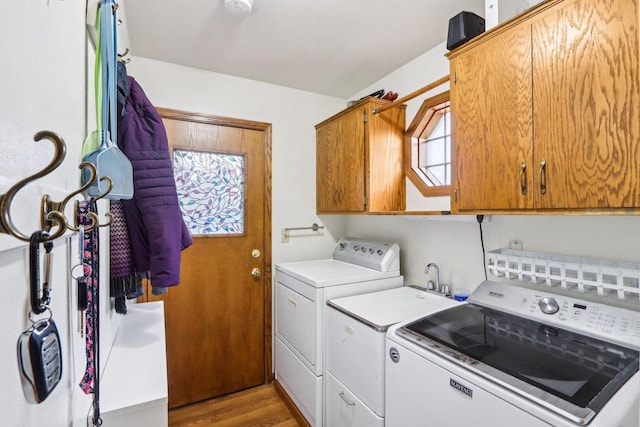 washroom with cabinet space, light wood-style floors, and independent washer and dryer