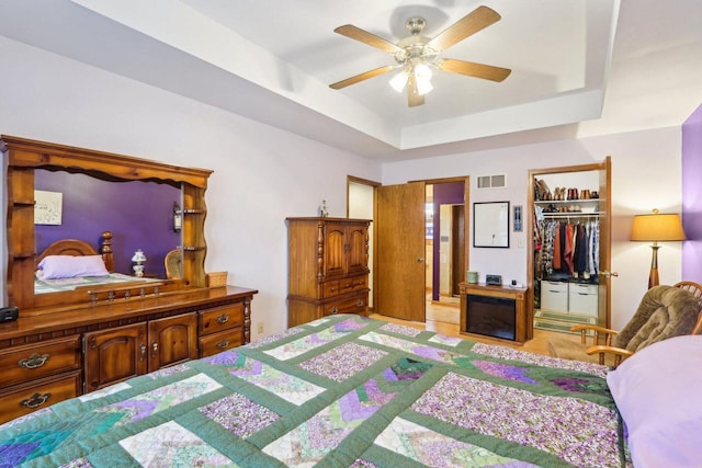 bedroom featuring visible vents, a ceiling fan, a spacious closet, a closet, and a tray ceiling